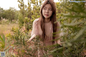 A woman in a white dress standing in the woods.