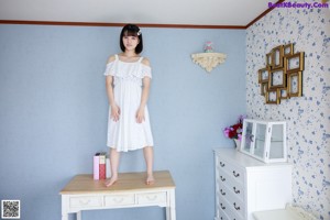 A woman in a white dress sitting on a wall.