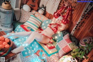 A woman in a red bikini sitting in front of a Christmas tree.