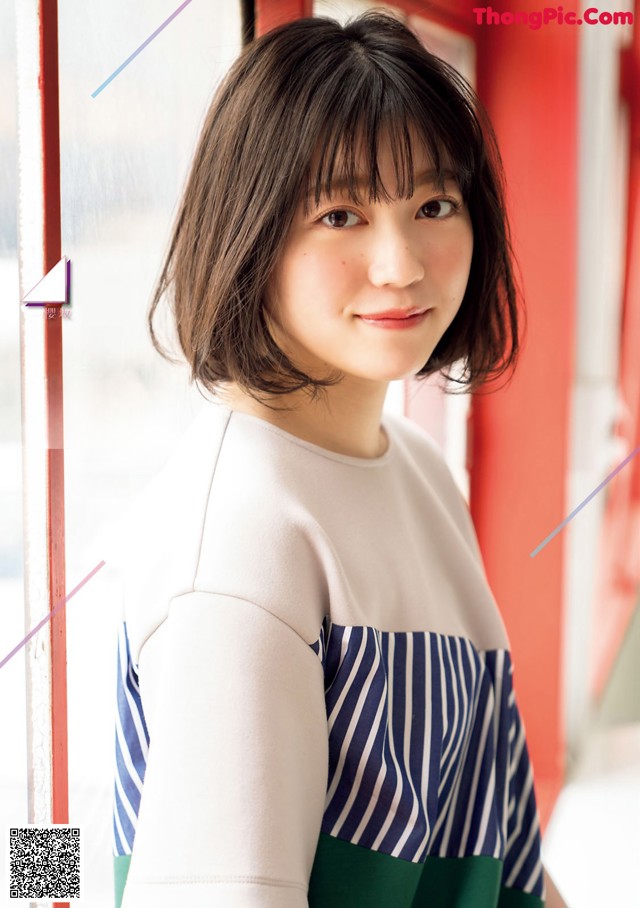 A woman in a striped shirt is posing for a magazine.