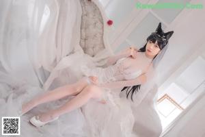 A woman in a wedding dress sitting on a white couch.