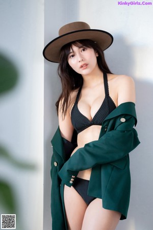 A woman in a black bikini and a green jacket.