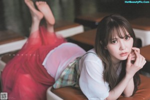 A woman sitting on top of a brown couch.