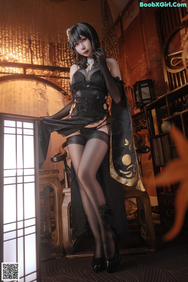 A woman in a black dress and stockings posing for a picture.