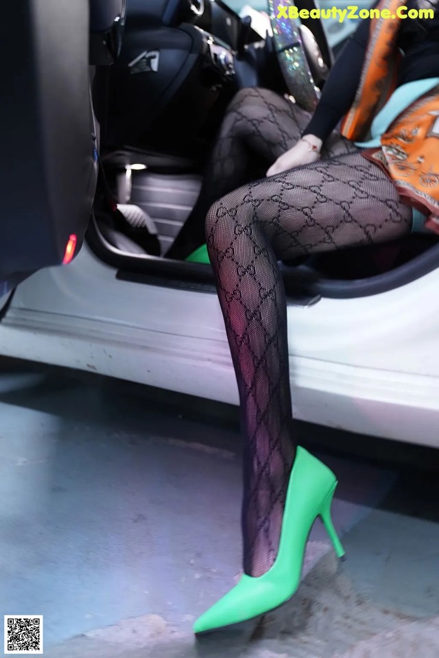 A woman sitting in the back seat of a car wearing fishnet stockings.