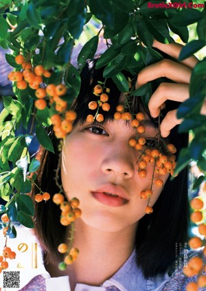 A woman in a yellow dress crouching under a large leaf.