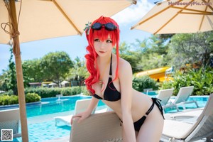 A woman in a bikini sitting by a swimming pool.