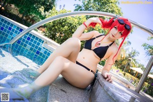 A woman in a black bikini standing next to a pool.