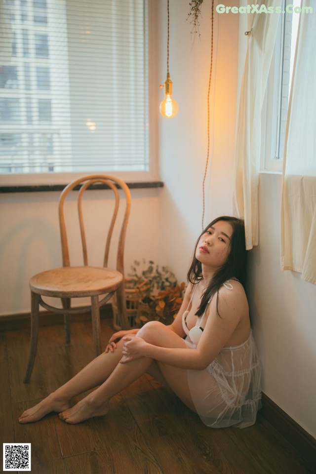 A woman sitting on the floor in front of a window.