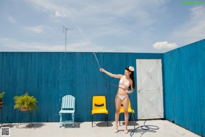A young girl in a straw hat is playing with a hose.