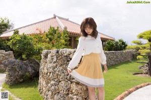 A woman in a white shirt and a yellow skirt posing for a picture.