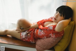 A woman in a red kimono sitting on the floor.