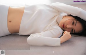 A woman laying on the floor with her hand on her head.