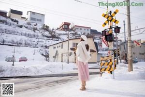 A woman sitting in the snow holding an umbrella.