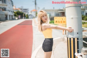 A woman in a white top and denim shorts posing for a picture.