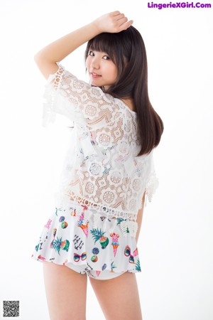 A young woman leaning against a white wall.