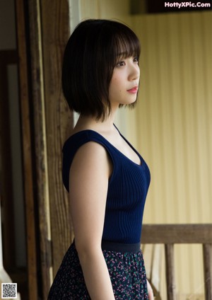 A woman in a black corset posing in front of a window.