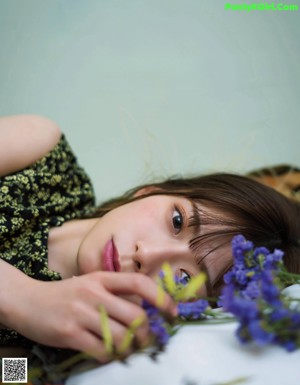 A woman laying on the grass in a blue shirt.