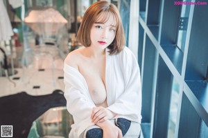 A woman in a black bikini sitting on a bed.