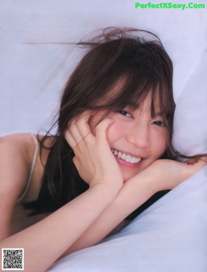 A woman in a white lingerie sitting on a bed.
