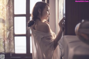 A woman laying on top of a bed next to a window.