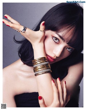 A woman with long black hair wearing a necklace and a ring.