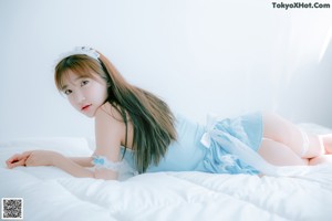 A woman in a blue dress standing on a bed.