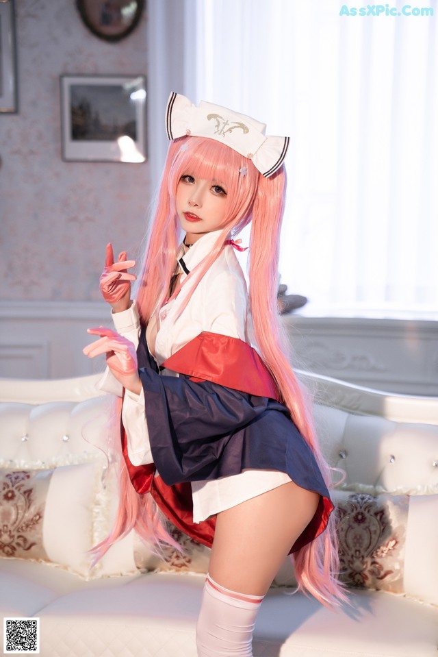 A woman in a sailor outfit posing on a white couch.