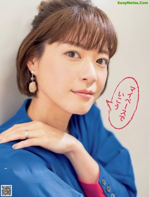 A woman in a blue shirt and black pants posing for a magazine.