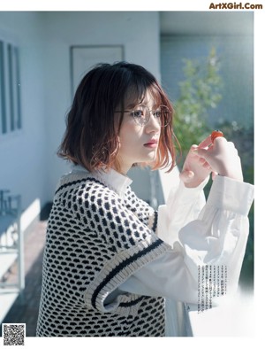 A woman standing on a balcony next to a white fence.